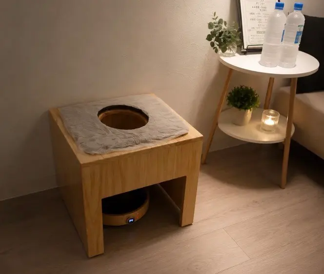 木製のよもぎ蒸し椅子。隣のテーブルにはキャンドルとボトル